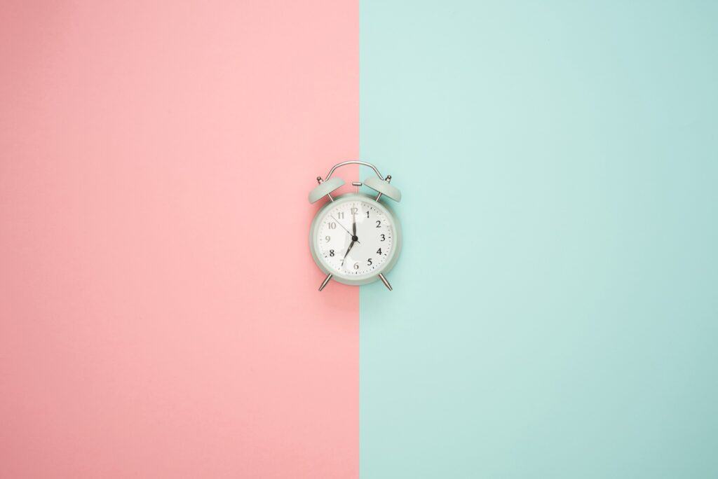 gezeigt wird ein Wecker, eine „Timebox“ auf rosa-türkisem Hintergrund